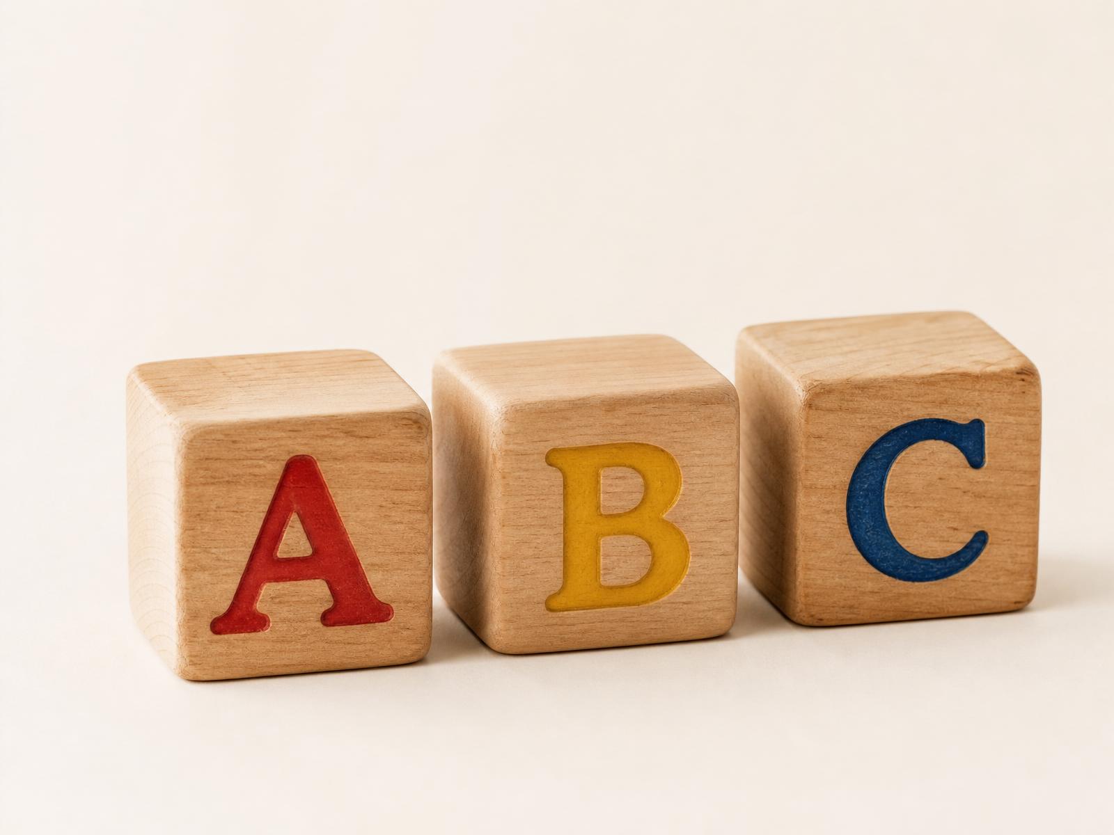 Realistic wooden ABC alphabet blocks in red, golden yellow, and deep blue